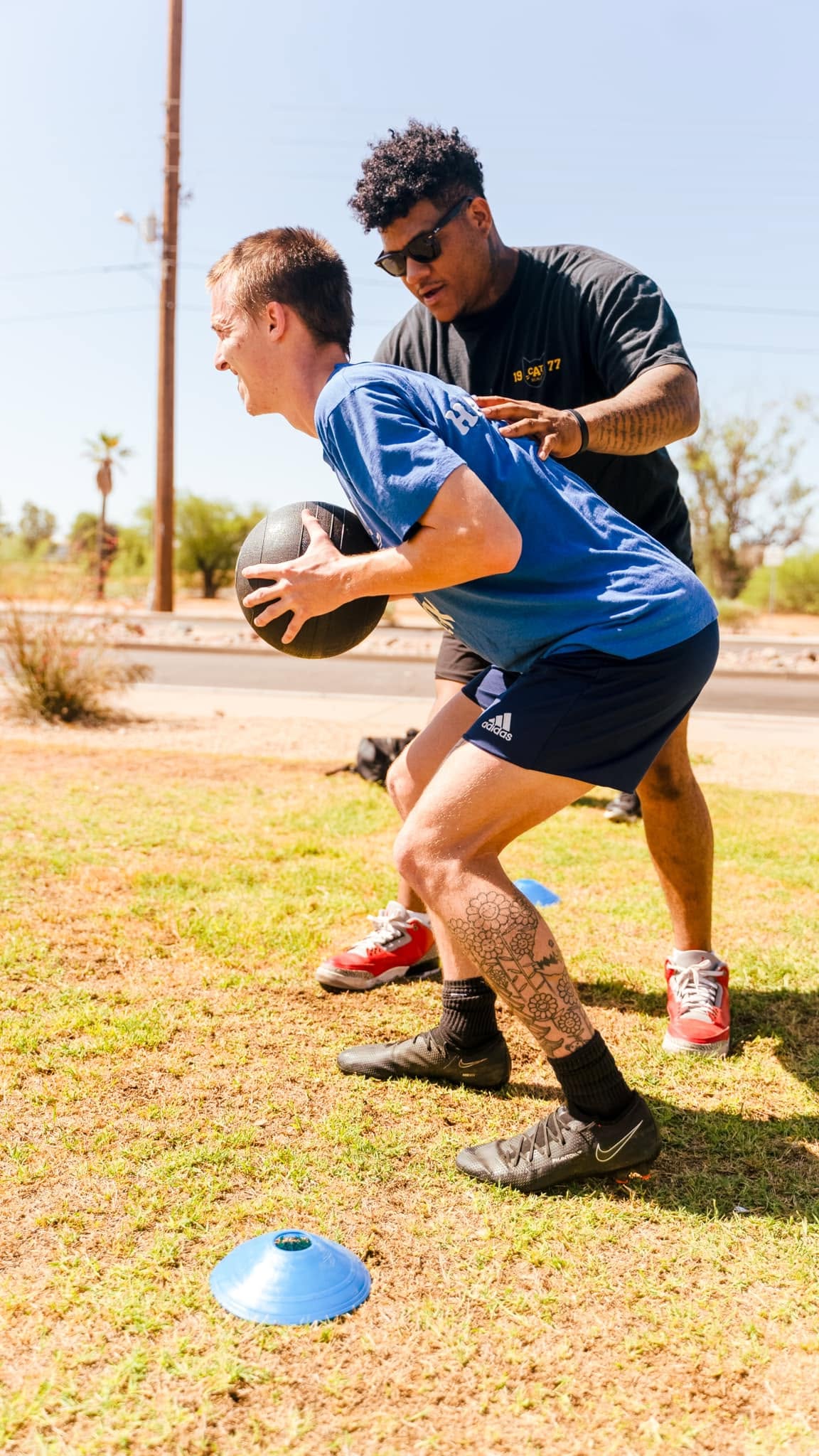 Stealth coach cueing a young athlete through a med ball agility drill outdoors in Phoenix
